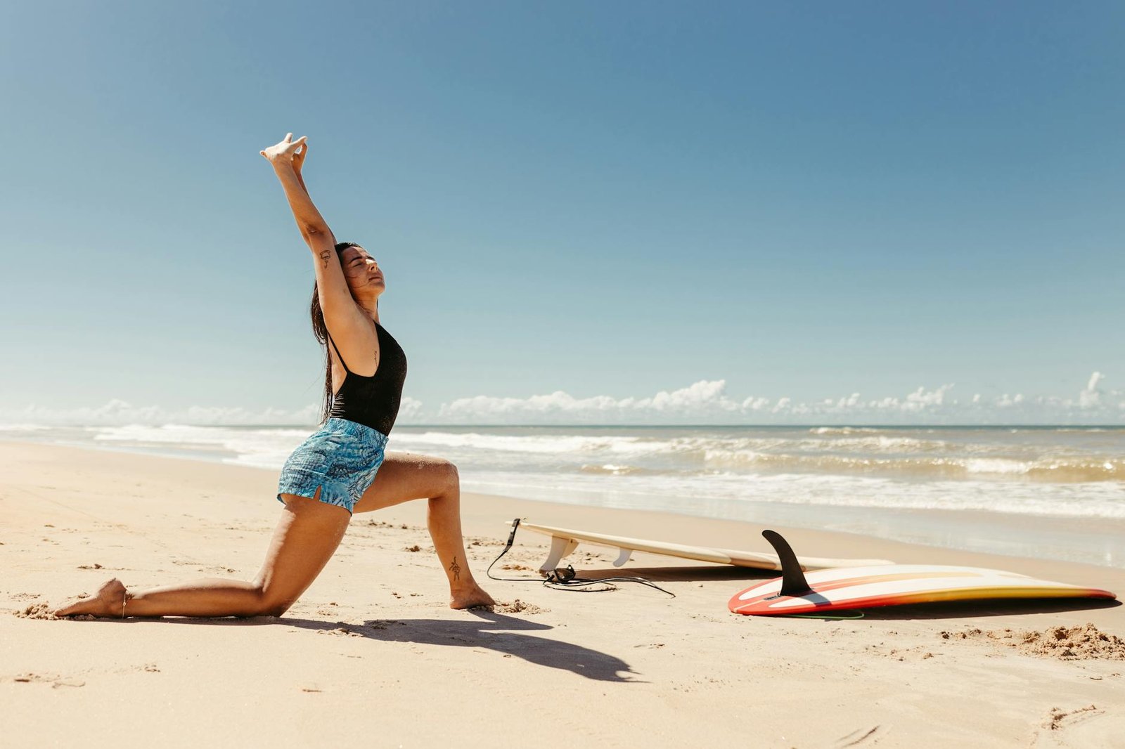 young woman stretching before surfing on the beach